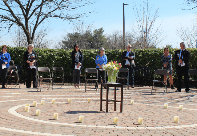 Bayview staff in a circle surrounding candles surrounding flowers